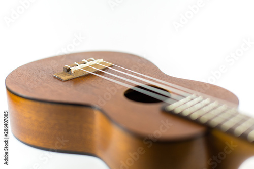 Close-up head of dark wooden ukulele music instrument Hawaiian guitar body with selected focus and copy space isolated over white background.