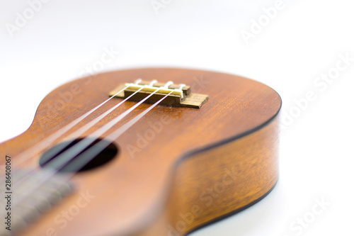 Close-up of dark brown wooden ukulele Hawaiian guitar with selected focus and copy space isolated on white background.