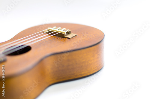 Close-up of dark brown wooden ukulele Hawaiian guitar with selected focus and copy space isolated on white background.