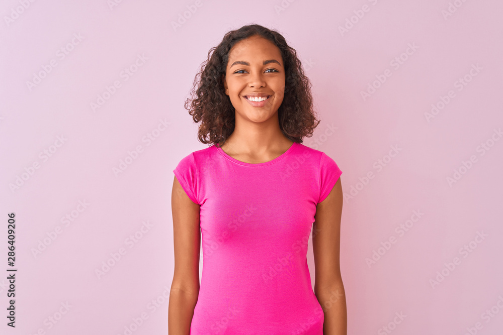 Young brazilian woman wearing t-shirt standing over isolated pink background with a happy and cool smile on face. Lucky person. Young brazilian woman wearing t-shirt standing over isolated pink background with a happy and cool smile on face. Lucky person.