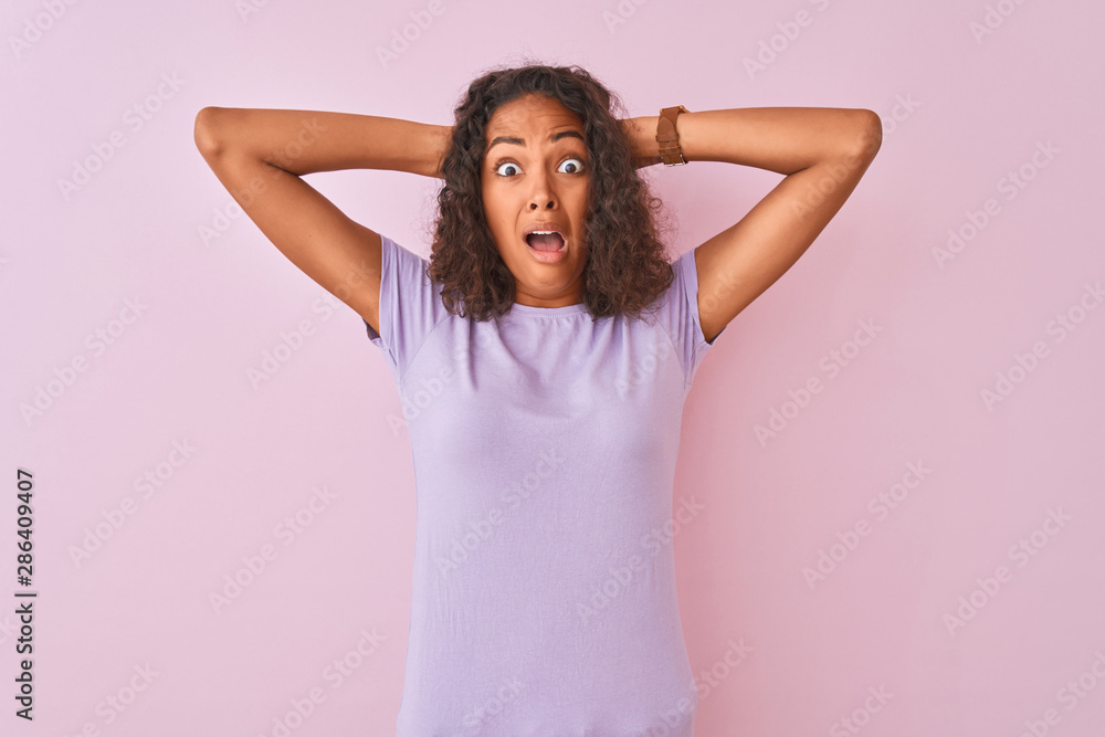 Young brazilian woman wearing t-shirt standing over isolated pink background Crazy and scared with hands on head, afraid and surprised of shock with open mouth Young brazilian woman wearing t-shirt standing over isolated pink background Crazy and scared with hands on head, afraid and surprised of shock with open mouth