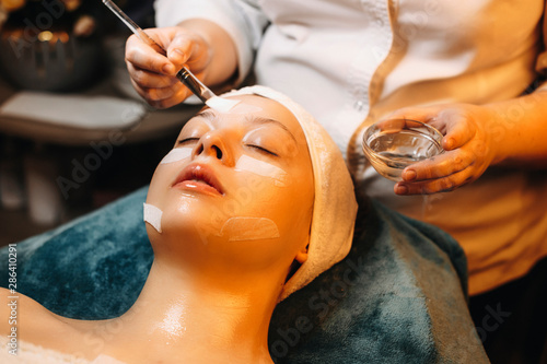 Charming caucasian woman leaning o n spa bed with closed eyes doing a anti age mask in a wellness spa center. photo