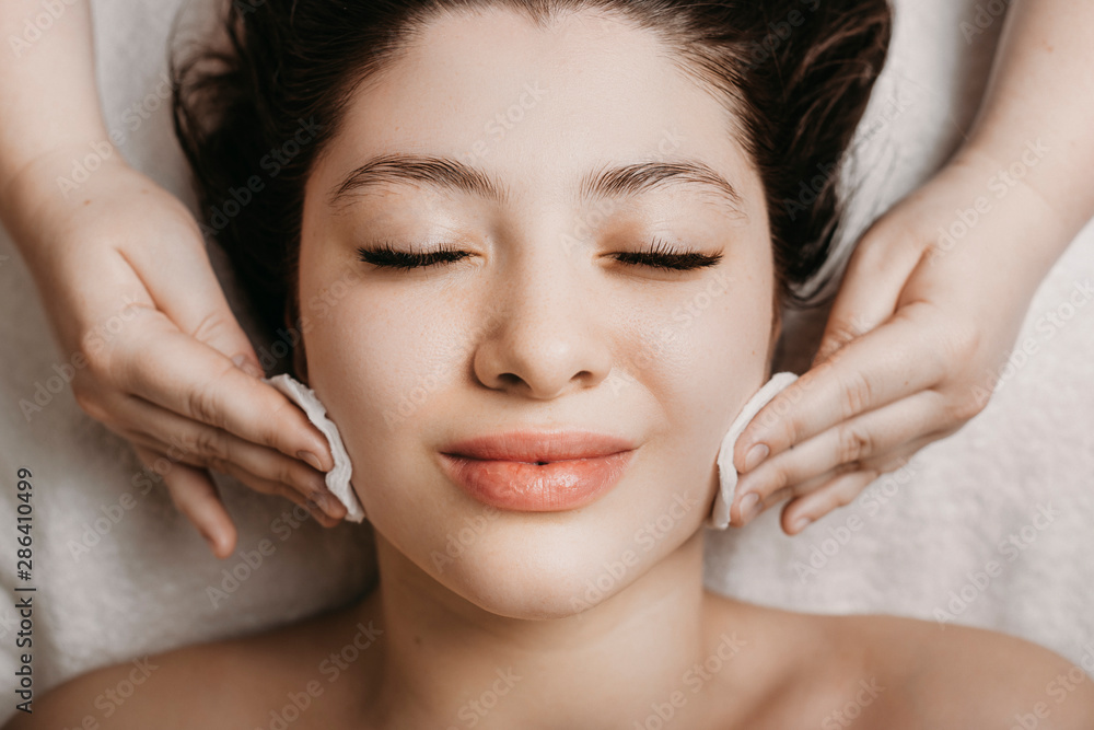 Close up of a cute young woman doing facial routine skin care in a wellness spa resort.
