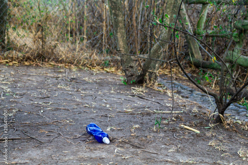 In the middle of the vegetation a girl cleans plastic bottles in a green bag