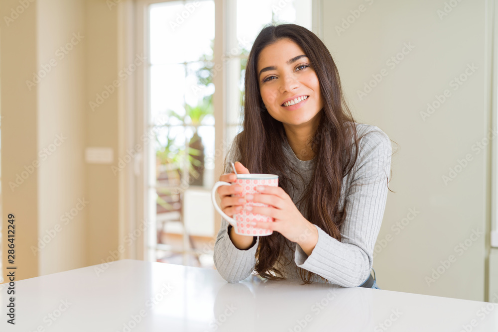 Beautiful young girl drinking a cup of coffee at home and smiling Beautiful young girl drinking a cup of coffee at home and smiling