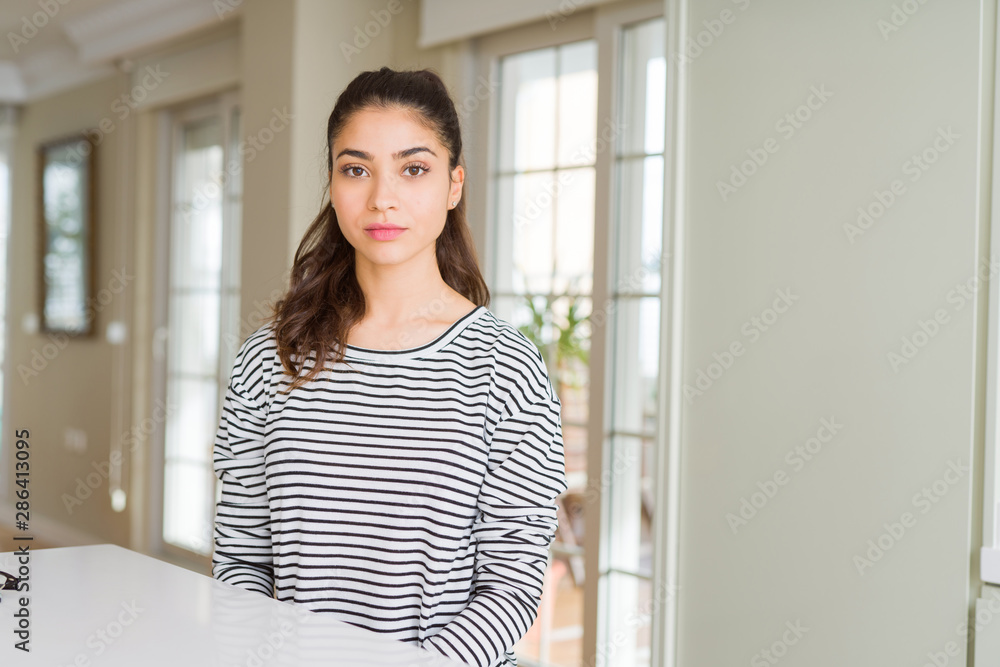 Young beautiful woman at home with serious expression on face. Simple and natural looking at the camera. Young beautiful woman at home with serious expression on face. Simple and natural looking at the camera.