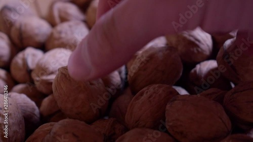 Dried walnuts in a wooden bowl. Picking some walnuts out of the bowl to eat them. Closeup shoh. Slowmo. photo