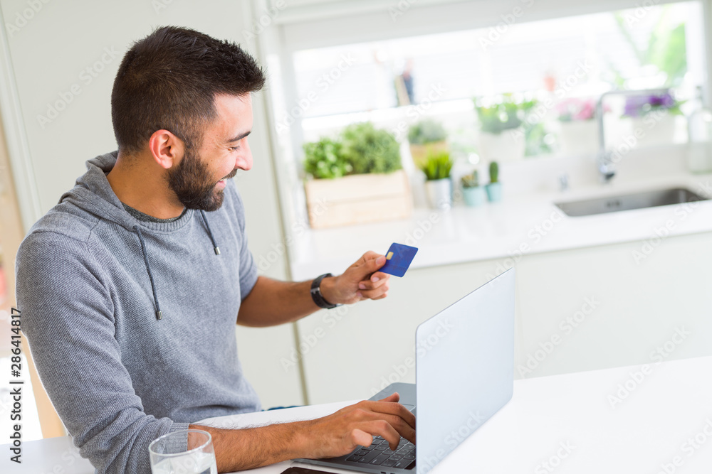 Man using credit card as payment metod when shopping online using laptop, blank screen concept