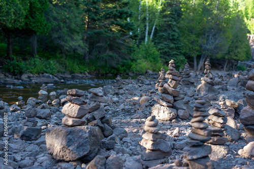 rows of stone cairns along peaceful forest stream