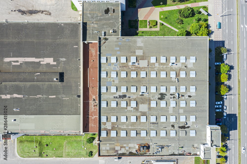 aerial top view of industrial warehouse roof with skylights and ventilation system