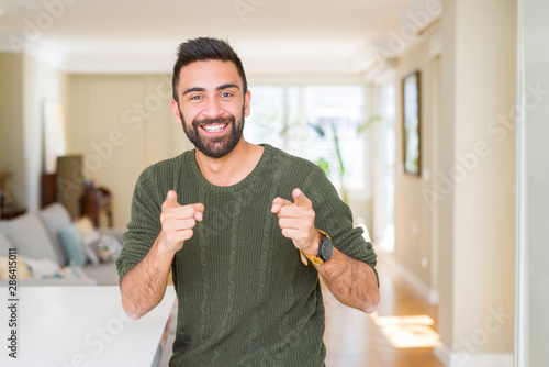 Handsome man pointing with arms and fingers, smiling cheerful with big smile on face photo