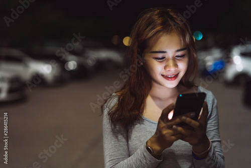 Beauty woman looking smartphone mobile phone at night on street her use technology application social media.