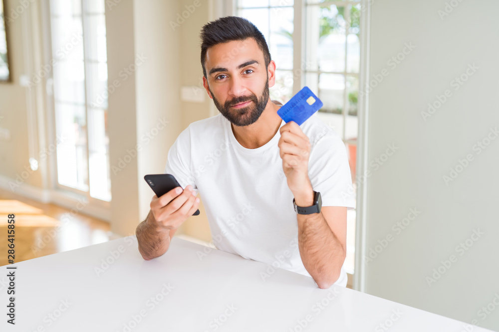 Handsome man using credit card to pay online with smartphone