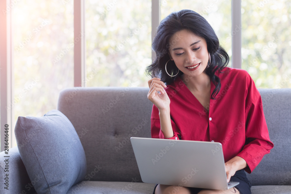 Asian woman using notebook computer on sofa.. Asian woman using notebook computer on sofa..