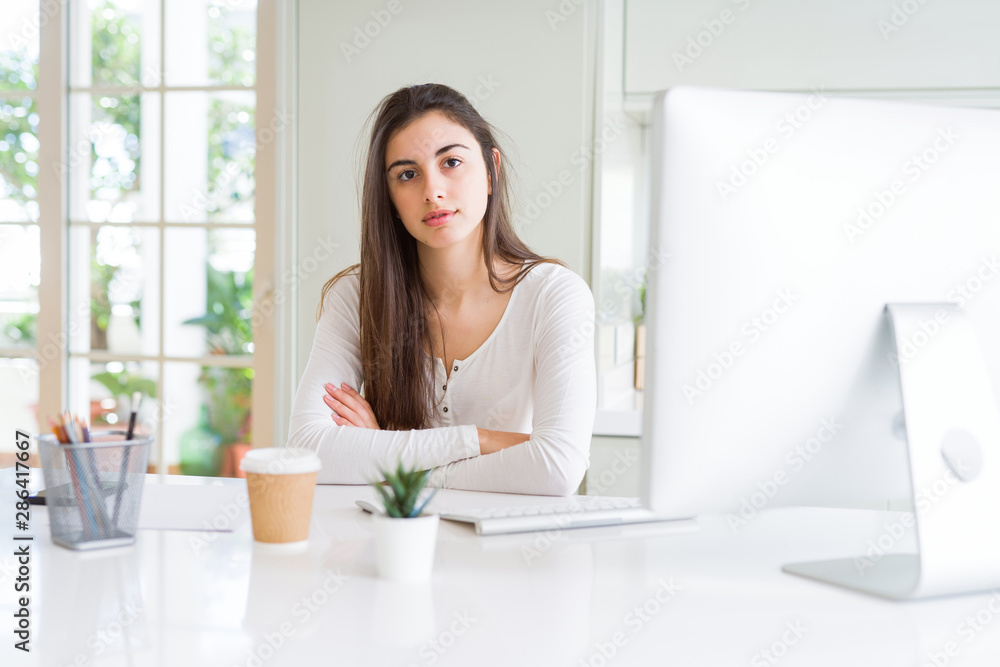 Beautiful young woman working using computer with serious expression on face. Simple and natural looking at the camera. Beautiful young woman working using computer with serious expression on face. Simple and natural looking at the camera.
