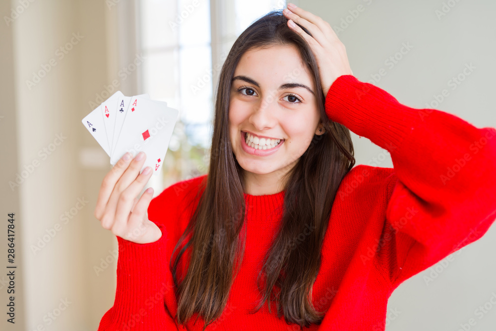 Beautiful young woman gambling playing poker stressed with hand on head, shocked with shame and surprise face, angry and frustrated. Fear and upset for mistake. Beautiful young woman gambling playing poker stressed with hand on head, shocked with shame and surprise face, angry and frustrated. Fear and upset for mistake.