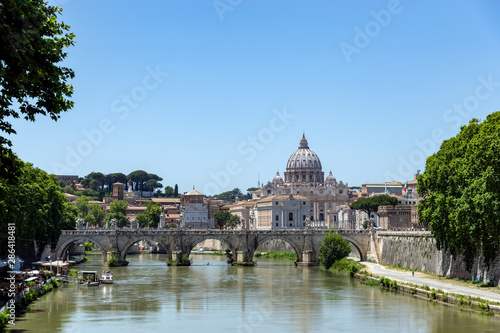 View of Sant'angelo bridge over the Tiber river with St. Peter's Basilica in background - Rome, Italy