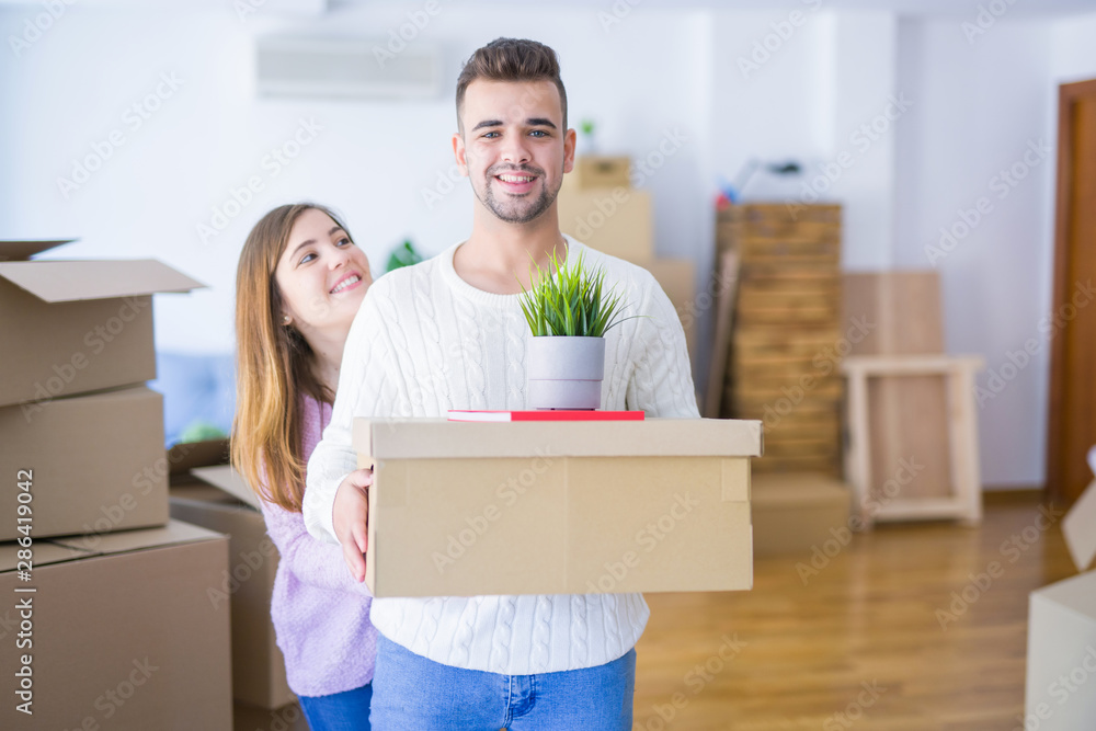Young beautiful couple in love moving to new home, holding cardboard boxes very happy and cheerful for new apartment Young beautiful couple in love moving to new home, holding cardboard boxes very happy and cheerful for new apartment