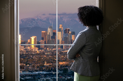 Fototapeta Black female business woman looking out the window of an office in Los Angeles