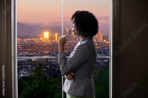 Fotografie Black female business woman looking out the window of an office in Los Angeles