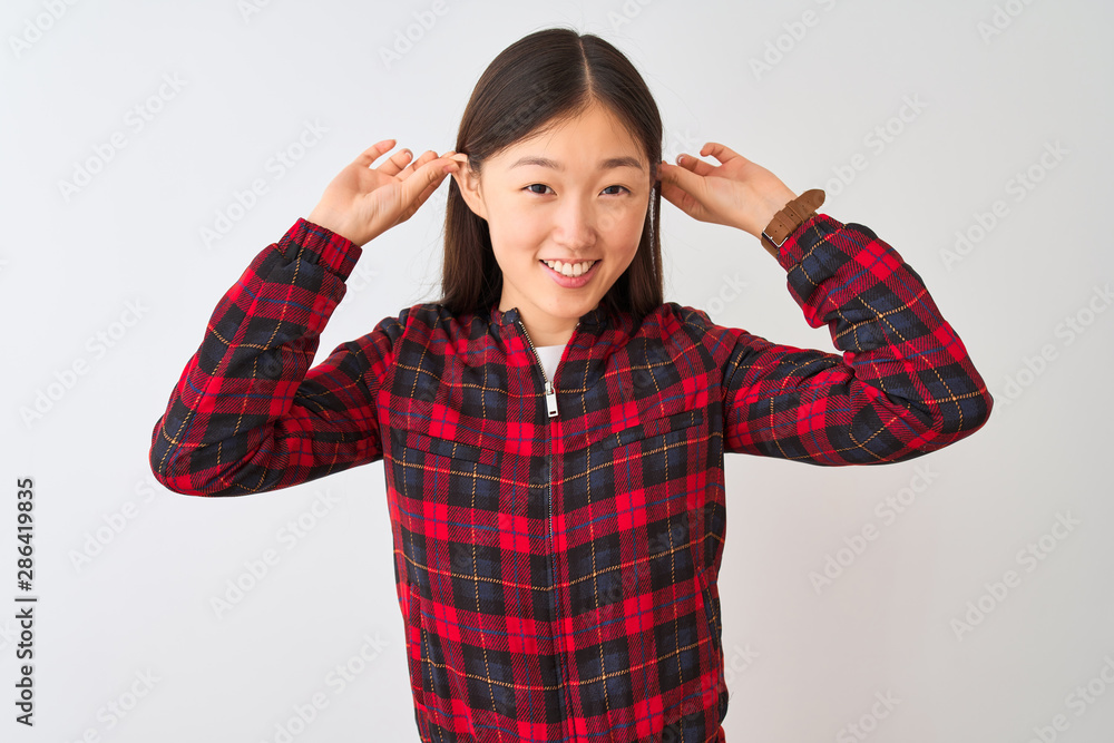 Young chinese woman wearing casual jacket standing over isolated white background Smiling pulling ears with fingers, funny gesture. Audition problem Young chinese woman wearing casual jacket standing over isolated white background Smiling pulling ears with fingers, funny gesture. Audition problem