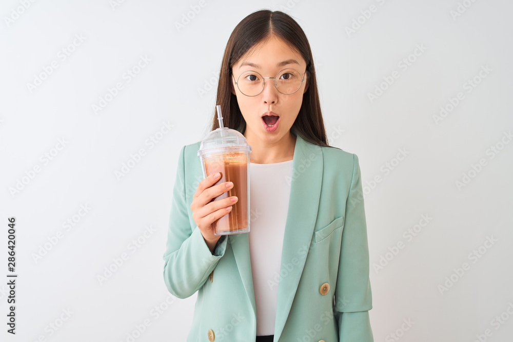 Young chinese woman drinking tomato smoothie over isolated white background scared in shock with a surprise face, afraid and excited with fear expression Young chinese woman drinking tomato smoothie over isolated white background scared in shock with a surprise face, afraid and excited with fear expression