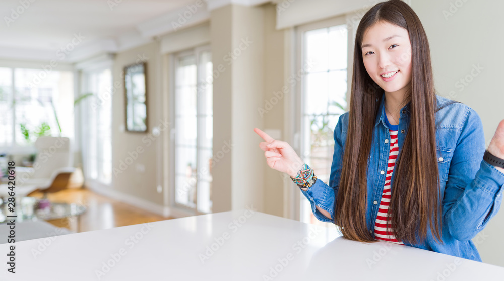 Young beautiful asian woman with long hair wearing denim jacket smiling confident pointing with fingers to different directions. Copy space for advertisement Young beautiful asian woman with long hair wearing denim jacket smiling confident pointing with fingers to different directions. Copy space for advertisement