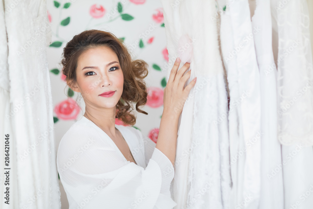 Bride is standing among white wedding dresses.. Bride is standing among white wedding dresses..