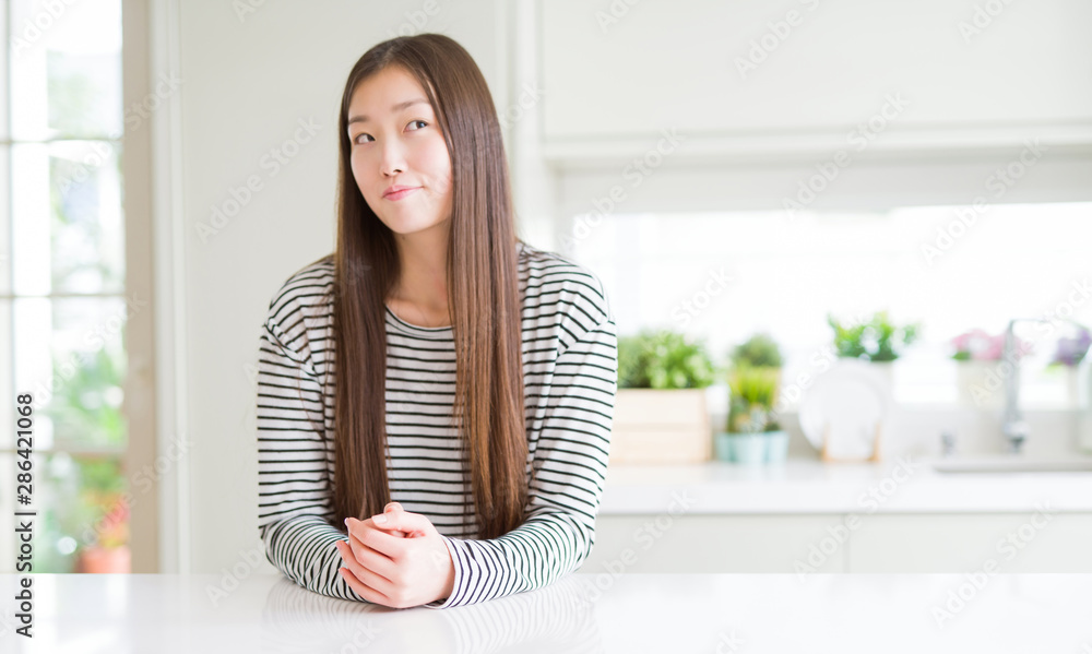 Beautiful Asian woman wearing stripes sweater smiling looking side and staring away thinking.