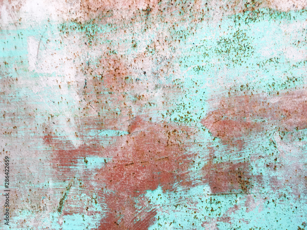 Old iron wall with scratches and rust covered with blue and green and pink paint. Grunge old background.