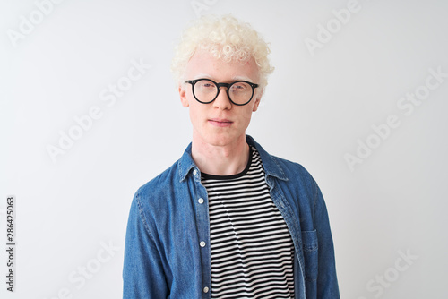Young albino blond man wearing denim shirt and glasses over isolated white background looking sleepy and tired, exhausted for fatigue and hangover, lazy eyes in the morning.