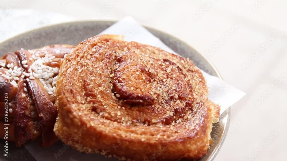 Tasty food. Fresh sugar cinnamon roll on a gray ceramic plate on a table in a street cafe. Tasty food. Fresh sugar cinnamon roll on a gray ceramic plate on a table in a street cafe.
