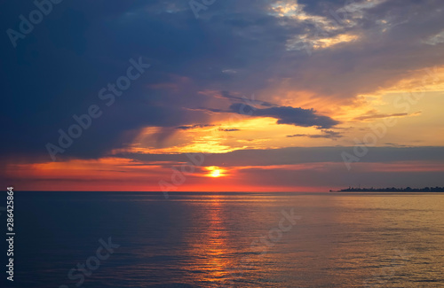 Amazing sunset on the ocean. View of dramatic cloudy sky and reflection of the sunlight on water. © vvicca
