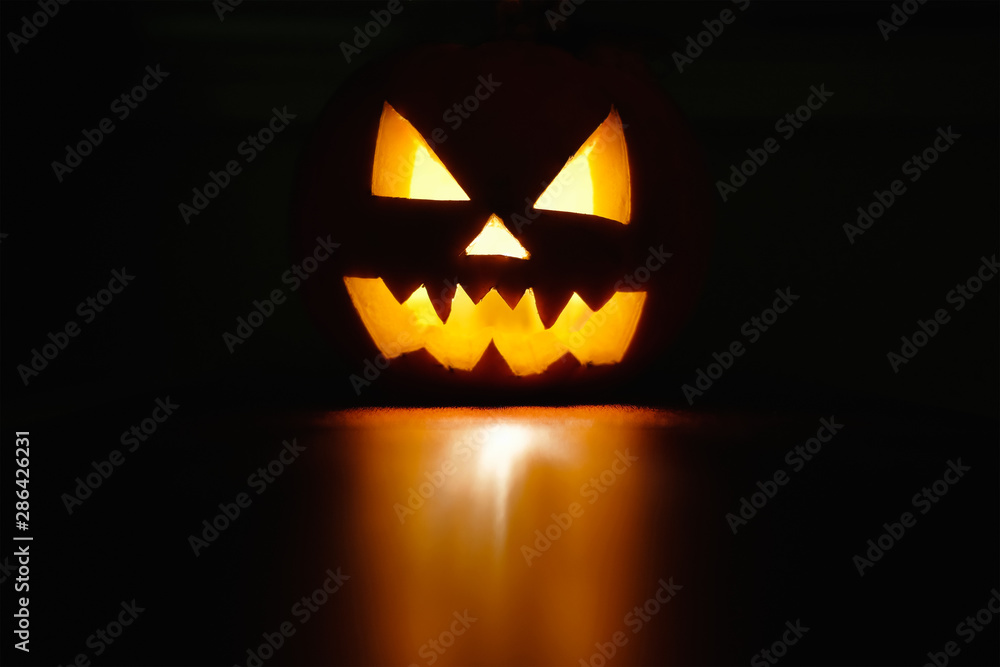 Fototapeta premium Halloween października symbol uroczystości wakacje, straszna dynia świecąca z odbiciem, czarne tło