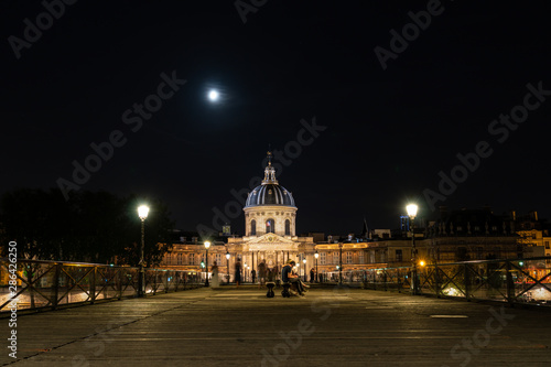 Institut de France and people walking on Pont des Arts at night - Paris, France. © UlyssePixel