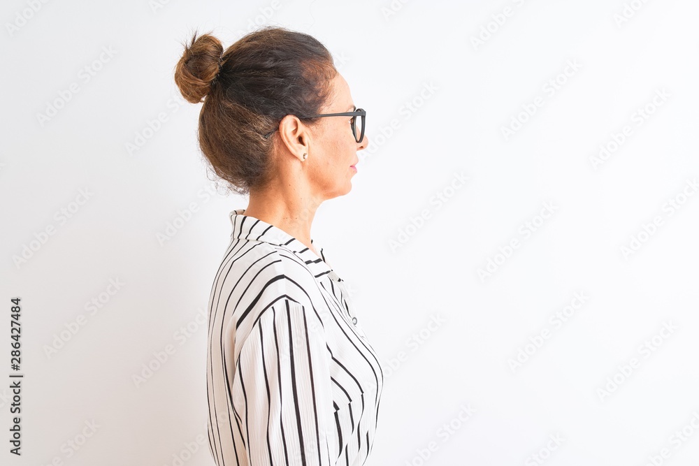 Middle age businesswoman wearing striped dress and glasses over isolated white background looking to side, relax profile pose with natural face and confident smile. Middle age businesswoman wearing striped dress and glasses over isolated white background looking to side, relax profile pose with natural face and confident smile.