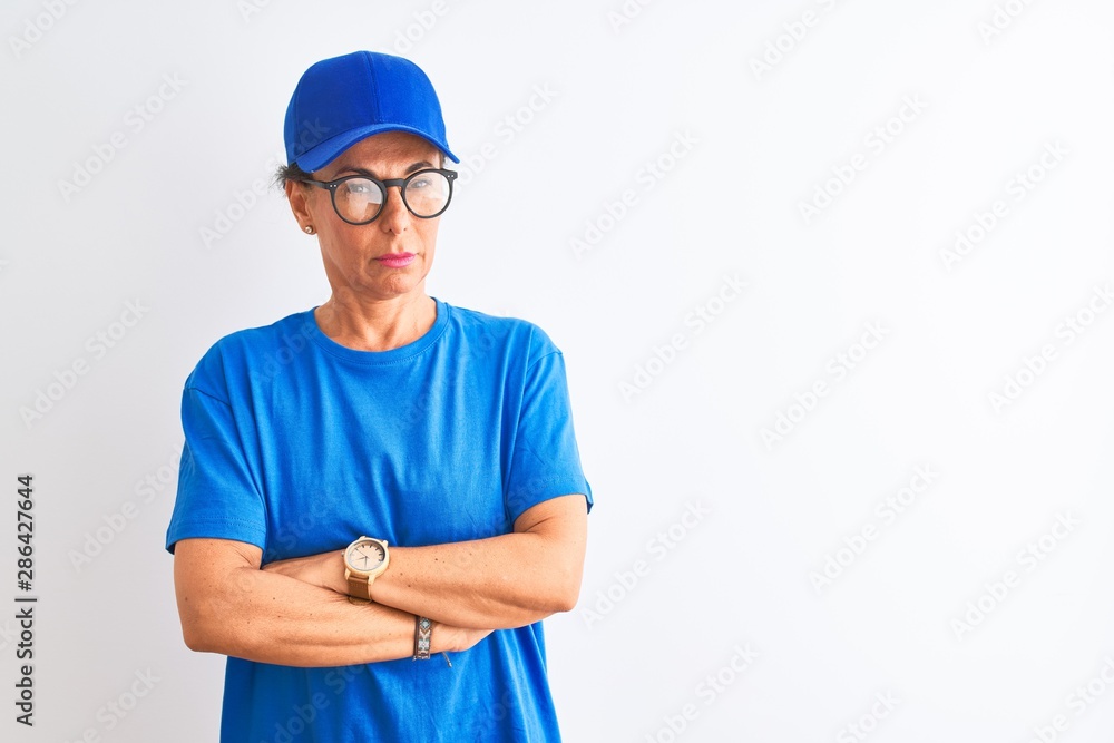 Senior deliverywoman wearing cap and glasses standing over isolated white background skeptic and nervous, disapproving expression on face with crossed arms. Negative person.