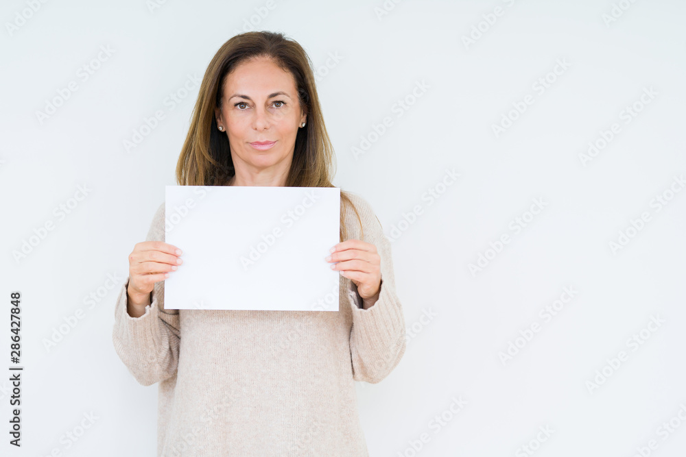 Middle age woman holding blank paper sheet over isolated background with a confident expression on smart face thinking serious Middle age woman holding blank paper sheet over isolated background with a confident expression on smart face thinking serious