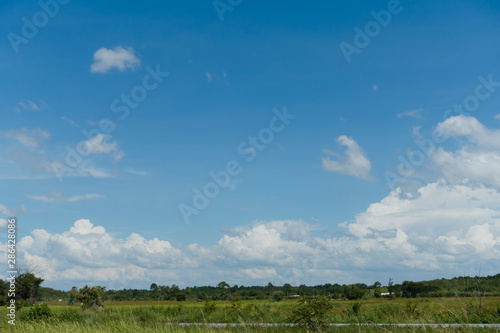 Bright sky filled with white clouds and green field