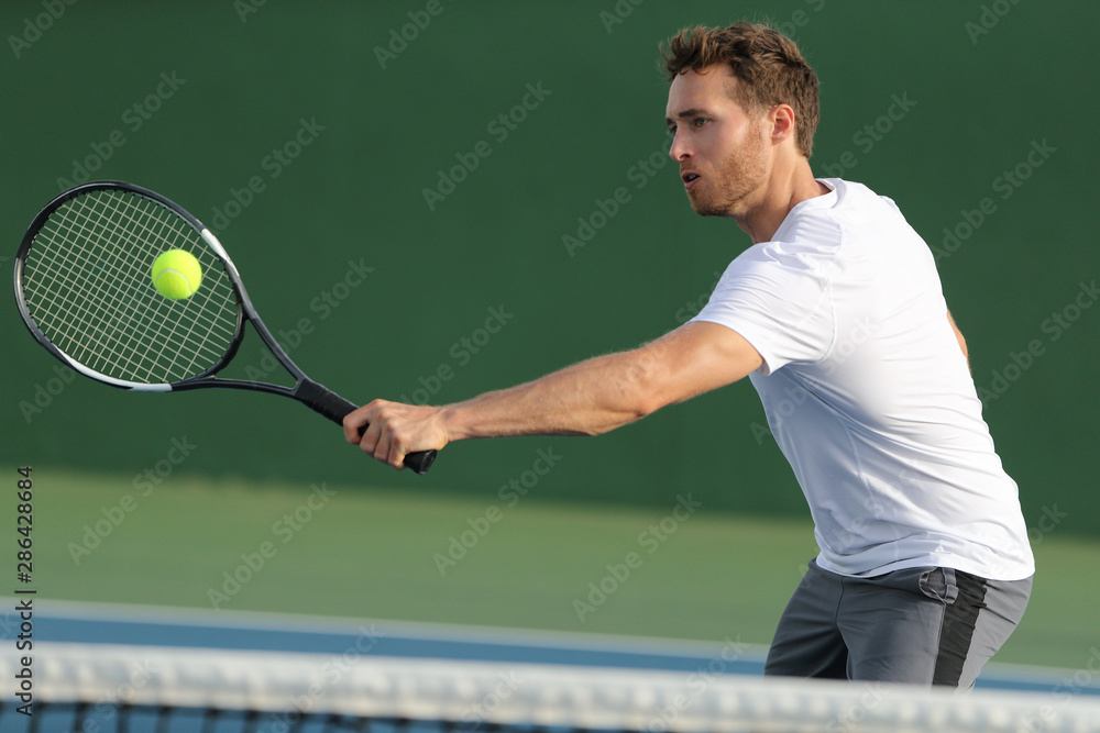Tennis player hitting ball with backhand racket on hard court. Man playing  game returning ball portrait. Stock Photo | Adobe Stock