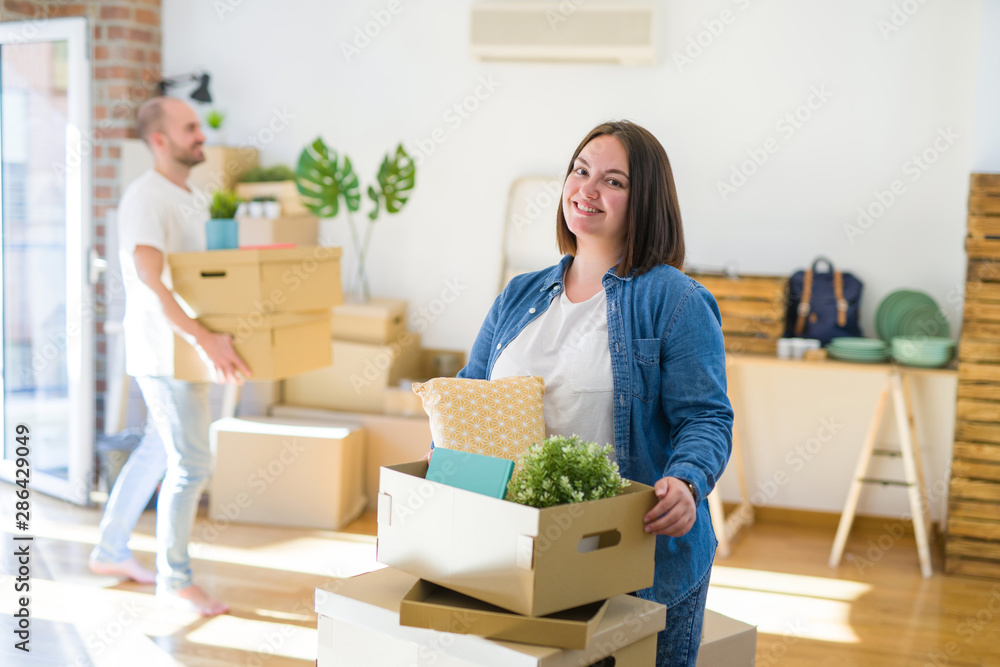 Young couple moving to new apartment, beautiful woman moving cardboard boxes and smiling happy Young couple moving to new apartment, beautiful woman moving cardboard boxes and smiling happy