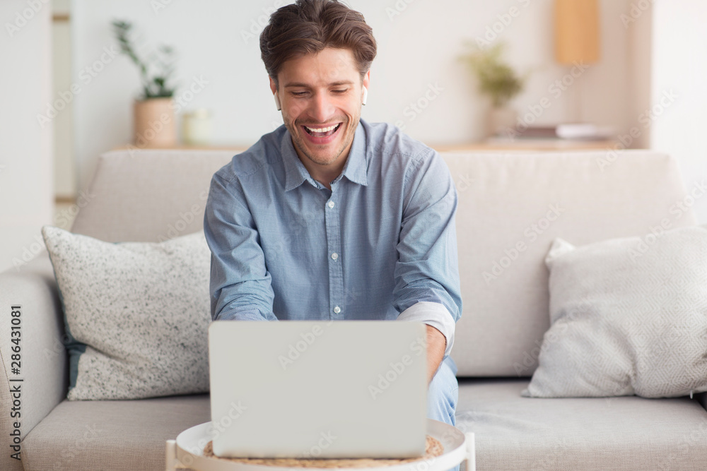 Smiling Guy Making Video Call Via Laptop Sitting On Couch Smiling Guy Making Video Call Via Laptop Sitting On Couch