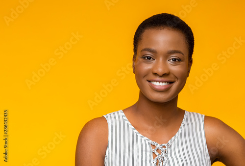 Attractive black girl smiling on yellow studio background © Prostock-studio