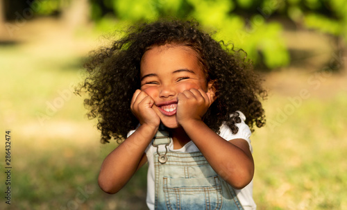 Photography Funny little afro girl touching cheeks and having fun