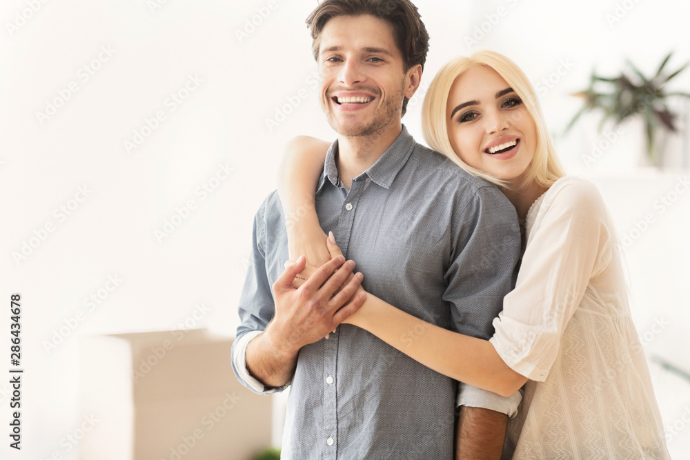 Naklejka premium Young Spouses Hugging Among Moving Boxes In New Apartment