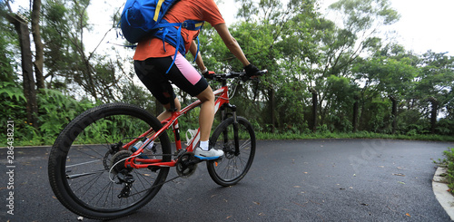 Fototapeta Naklejka Na Ścianę i Meble -  Woman cyclist riding mountain bike on tropical rainforest trail