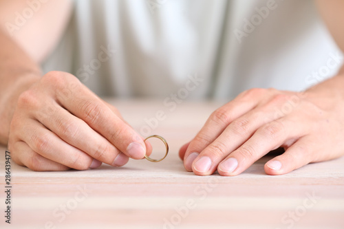 Man with wedding ring at home, closeup. Concept of divorce