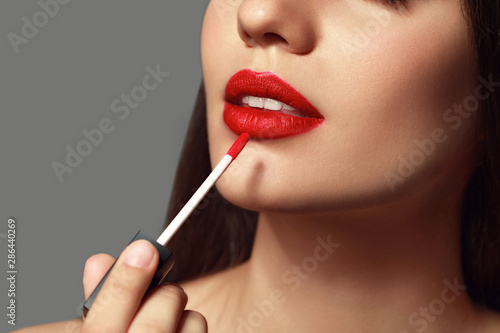 Beautiful young woman with bright lipstick on grey background, closeup photo