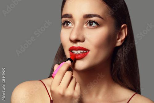 Beautiful young woman with bright lipstick on grey background