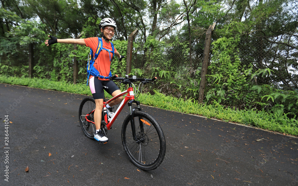Fototapeta premium Woman cyclist riding mountain bike on tropical rainforest trail